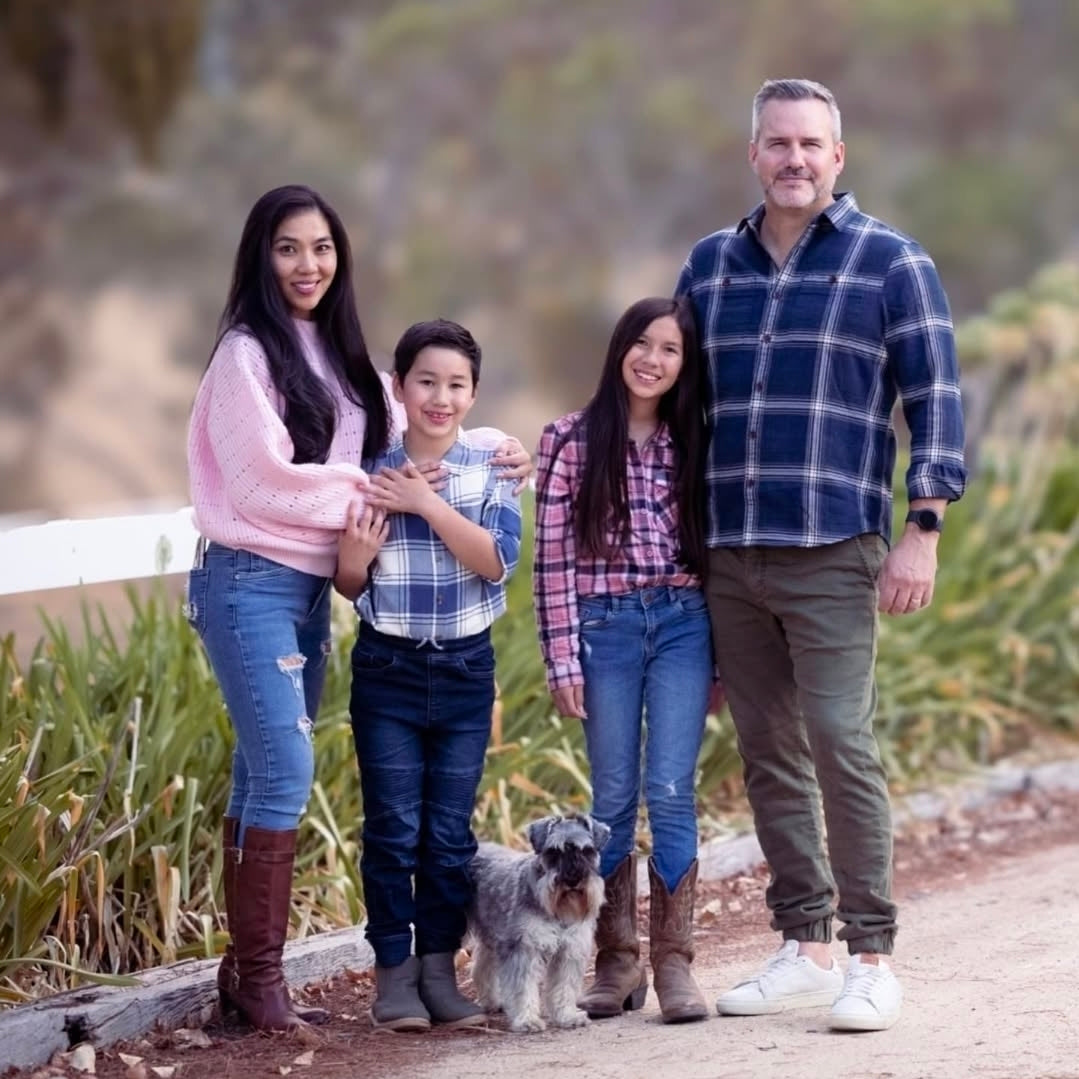 Family of four with a dog standing on a path outdoors