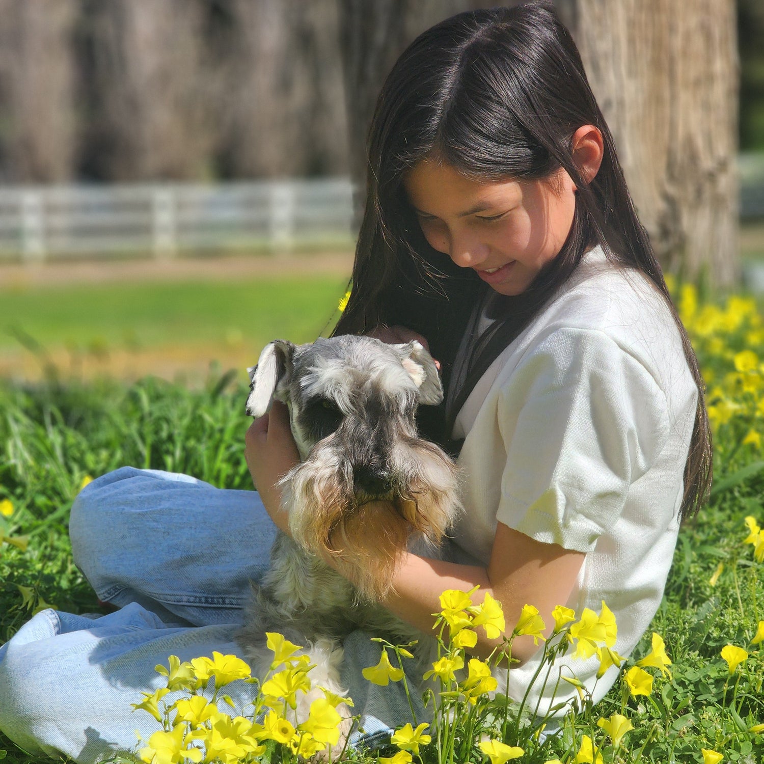 Woman holding a small dog in a field of yellow flowers
